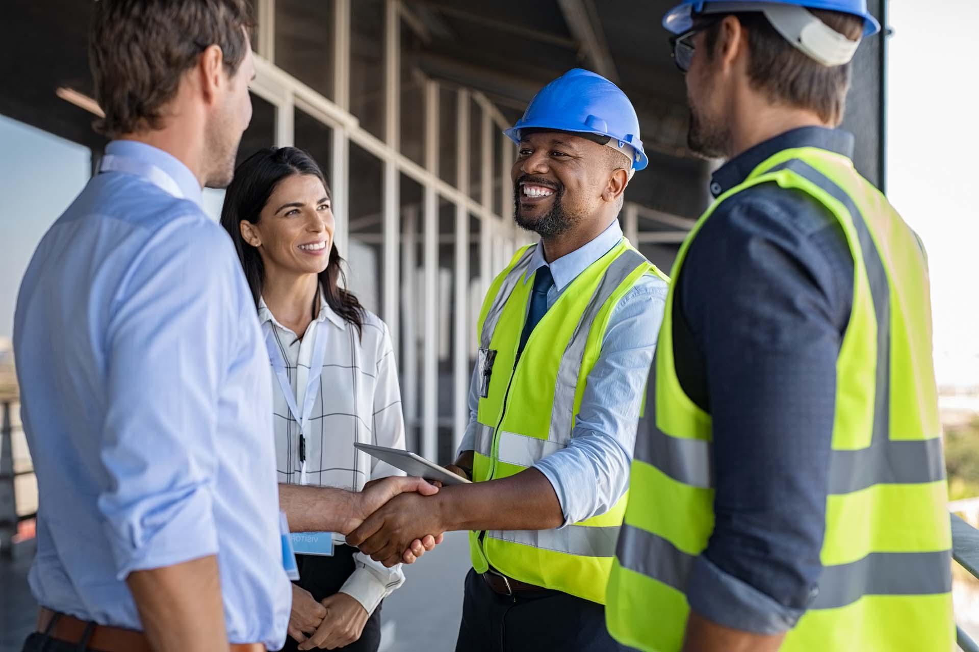 Smiling engineer shaking hands at construction site with architect.